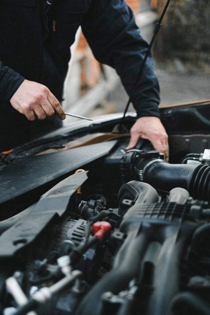 Person in Black Long Sleeves Repairing the Car Engine